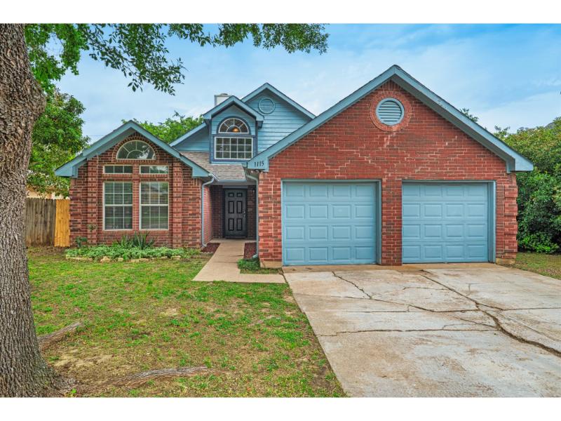 Front exterior of 1115 Cherrytree Drive Arlington TX 76001 with brick facade and two-car garage